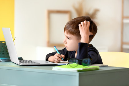 Little schoolboy doing lessons online at home