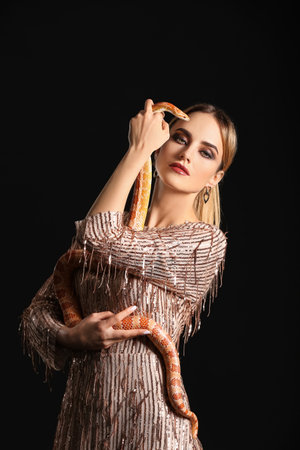 Sexy young woman with snake on black background