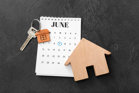 Calendar with pay rent mark, figure of house and key with keychain on dark backgroundの写真素材