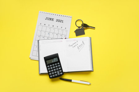 Calendar with pay rent mark, notebook, calculator and key from house with keychain on color backgroundの写真素材