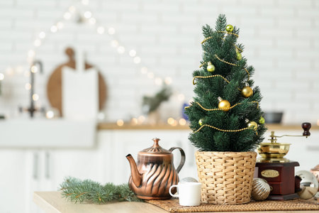 Small Christmas tree with teapot and coffee grinder on table in kitchenの写真素材