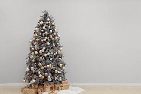 Glowing Christmas tree with presents near light wallの写真素材