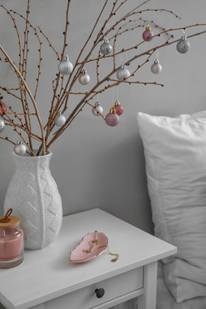 Vase with tree branches, Christmas balls, candle and jewelry on table in bedroomの写真素材