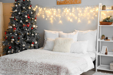 Interior of bedroom with Christmas tree, glowing lights and shelving unitの写真素材