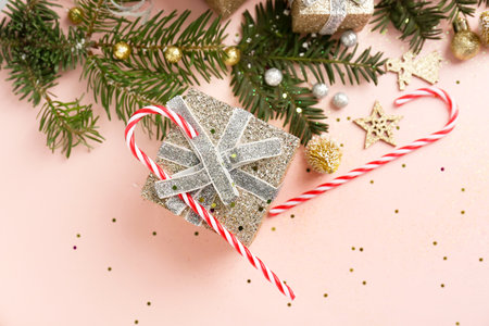Composition with Christmas gift, candy canes, decorations and fir branches on pink backgroundの写真素材