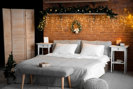 Interior of bedroom with Christmas wreath, fir branches and glowing lightsの写真素材