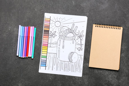 Coloring page, felt-tip pens and notebook on dark backgroundの写真素材