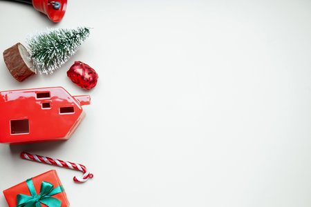 House shaped candle holder with Christmas bell, toys and gift on beige backgroundの写真素材