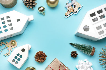 Frame made of house shaped candle holders, fir cones and Christmas toys on blue backgroundの写真素材