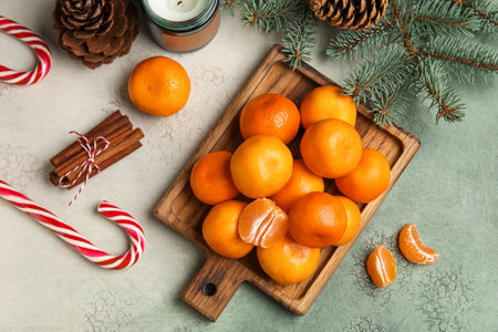 Wooden board with ripe tangerines, candy canes, cinnamon and fir branch on grunge backgroundの写真素材