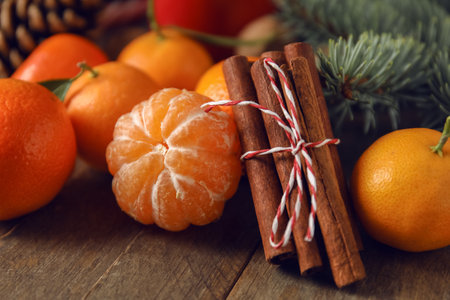Ripe tangerines and cinnamon sticks on wooden table, closeupの写真素材