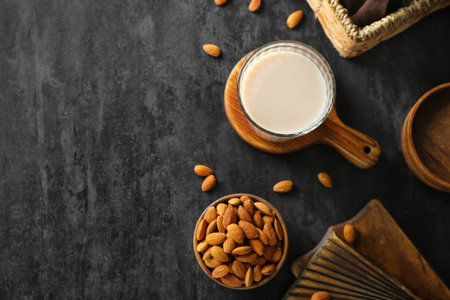 Wooden board with glass of almond milk and nuts on dark backgroundの写真素材