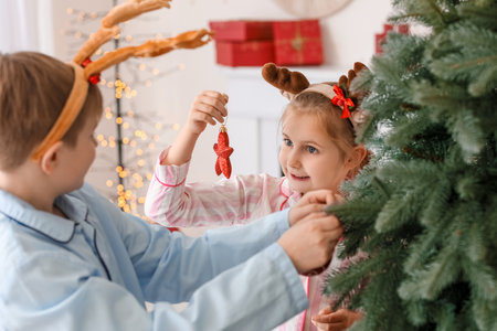 Happy little children decorating Christmas tree at homeの写真素材