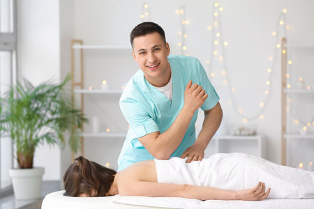 Massage therapist working with patient in medical centerの写真素材