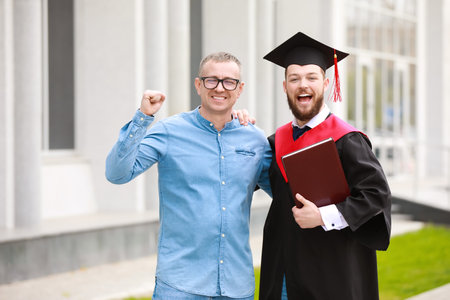 Happy young man with his father on graduation dayの写真素材