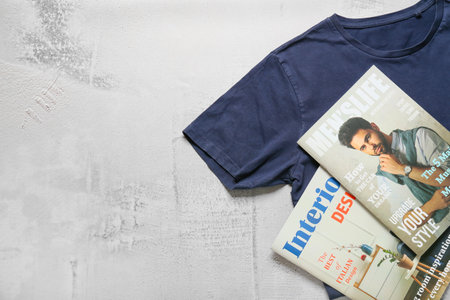 Stylish t-shirt and magazines on light background