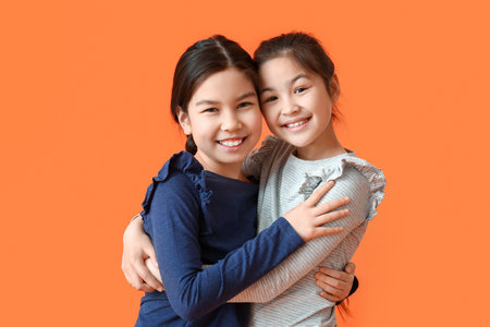 Cute little sisters on color backgroundの写真素材