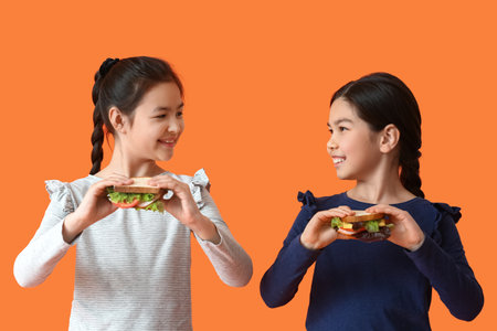 Little girls with tasty sandwiches on color backgroundの写真素材