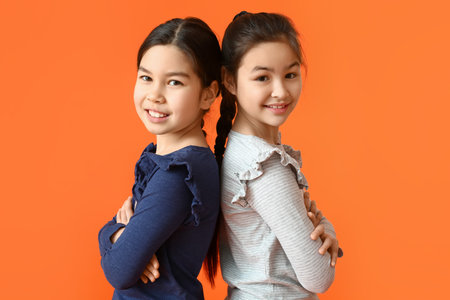 Cute little sisters on color backgroundの写真素材