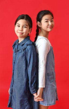 Cute little sisters on color backgroundの写真素材