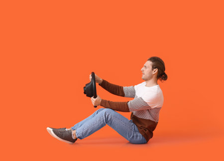 Young man with steering wheel on color background