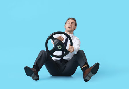 Displeased young man with steering wheel on color background