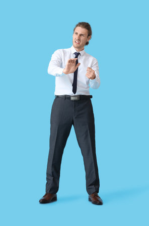 Angry young man with imaginary steering wheel on color backgroundの写真素材