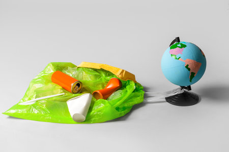 Bag with garbage and globe on gray background. Ecology conceptの写真素材