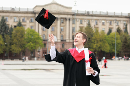 Portrait of male graduating student throwing cap outdoors