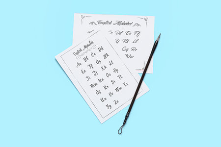 Paper sheets with English alphabet and brush on blue background