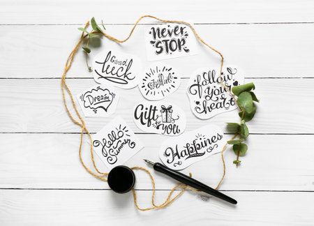 Paper pieces with different text and nib pen on white wooden background