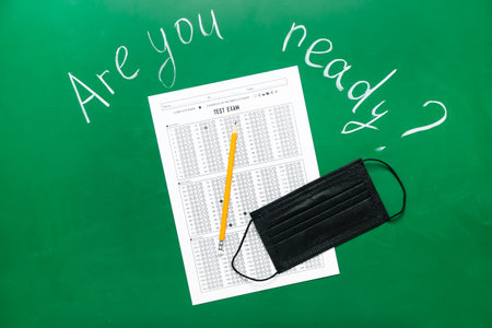 Answer sheet, pencil and mask on blackboard with text ARE YOU READY?