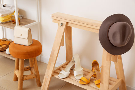 Wooden shoes stand with stylish hat near light wallの写真素材