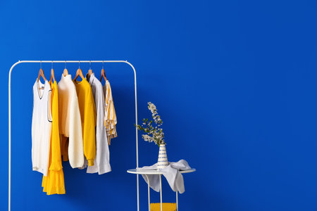 Rack with stylish clothes and table on color backgroundの写真素材