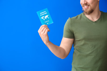Young man with immune passport on color backgroundの写真素材