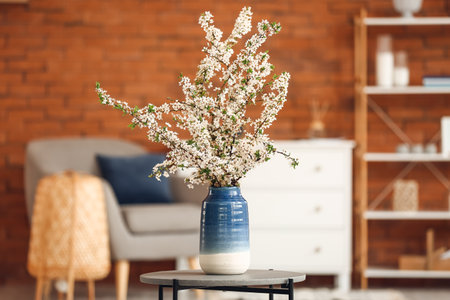 Vase with beautiful blossoming branches on table in roomの写真素材