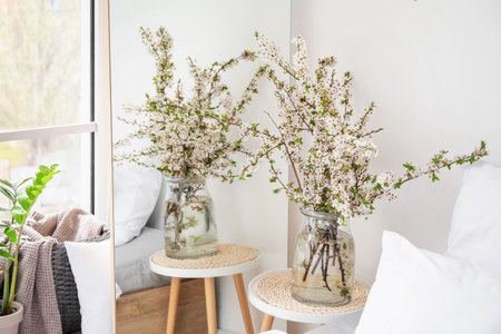 Vase with blossoming branches on table near mirrorの写真素材