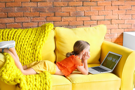 Cute girl watching cartoons at homeの写真素材