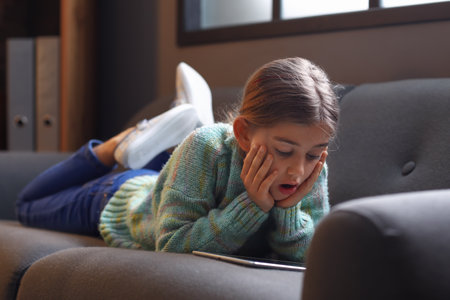 Surprised girl watching cartoons at homeの写真素材