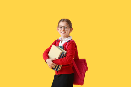 Cute little school girl with books on color backgroundの写真素材