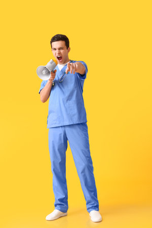 Protesting male doctor with megaphone on color backgroundの写真素材