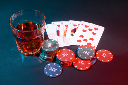 Poker chips, playing cards and glass of beverage on dark backgroundの写真素材