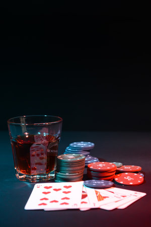 Poker chips, playing cards and glass of beverage on dark backgroundの写真素材