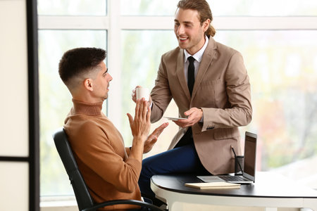 Man harassing his male colleague in officeの写真素材