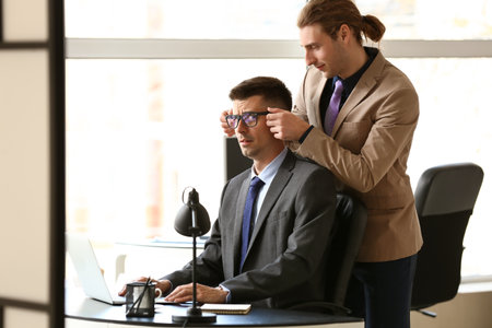Man harassing his male colleague in officeの写真素材