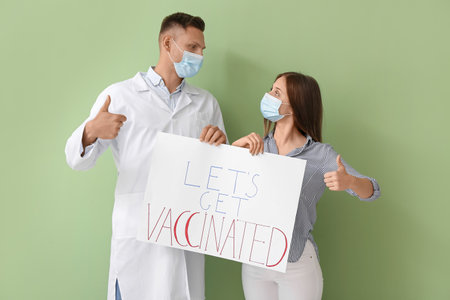Doctor and patient holding poster with text LET'S GET VACCINATED on color backgroundの写真素材