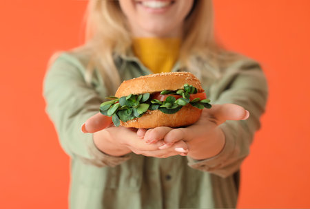 Young woman with tasty vegan burger on color background, closeupの写真素材