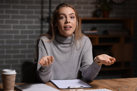 Young woman video chatting in office at nightの写真素材