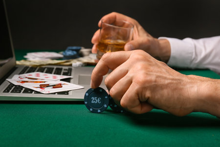 Man with laptop playing poker online at table in casinoの写真素材