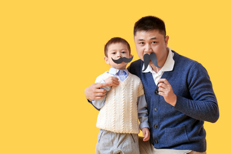 Happy father and his little son with party decor on color backgroundの写真素材